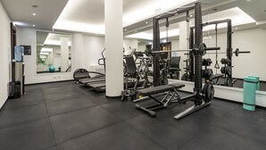 A modern gym with various exercise equipment, a large mirror, and a clean, tiled floor. - River Château Hotel (Rome)