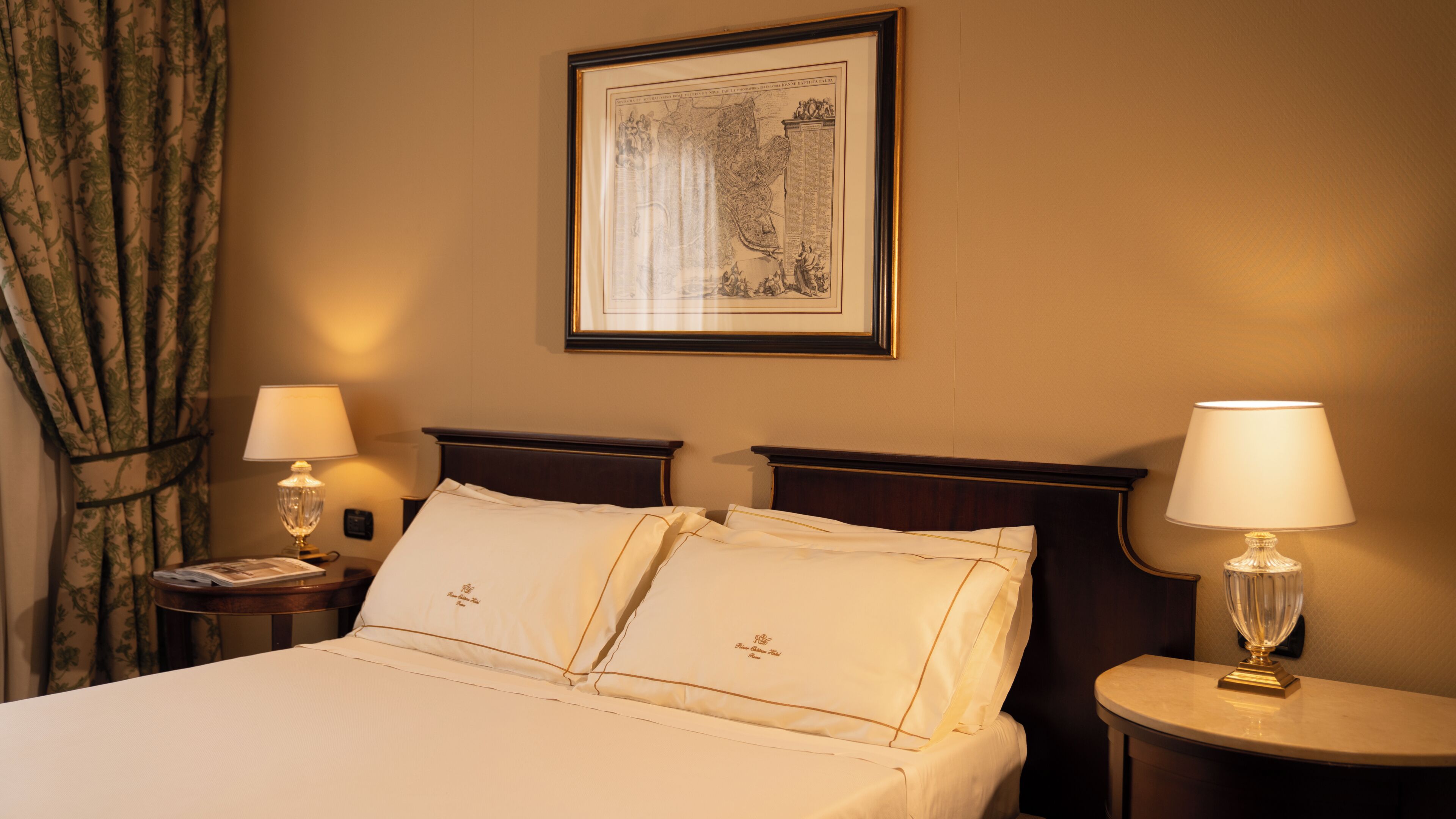 Une chambre d’hôtel avec un grand lit, deux tables de chevet, une carte encadrée accrochée au mur et une fenêtre avec des rideaux.