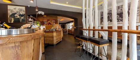 A modern bar area with a wooden counter, bar stools, and a decorative white column structure.