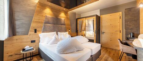 A modern bedroom with a lofted sleeping area, a wooden ceiling, and a desk with a chair.