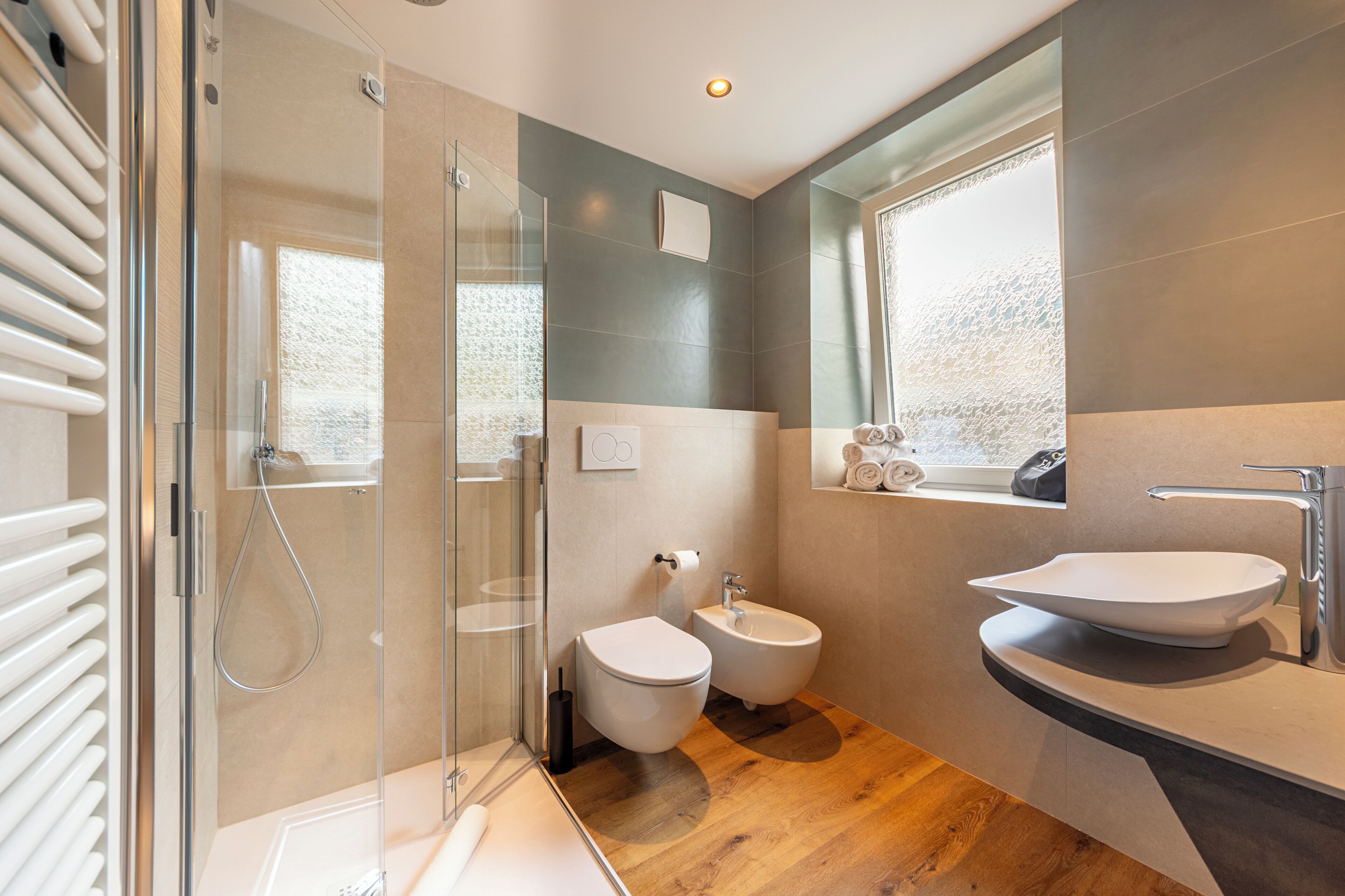 A modern bathroom with a glass shower enclosure, a bidet, a toilet, and a sink with a vanity.