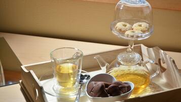 A tray with a glass teapot, a glass cup, a bowl of cookies, and a sugar bowl.