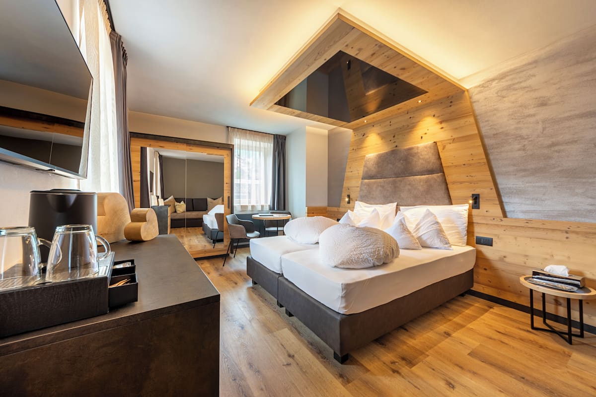 A modern bedroom with a lofted sleeping area, a wooden ceiling, and a cozy seating area with a sofa and coffee table.