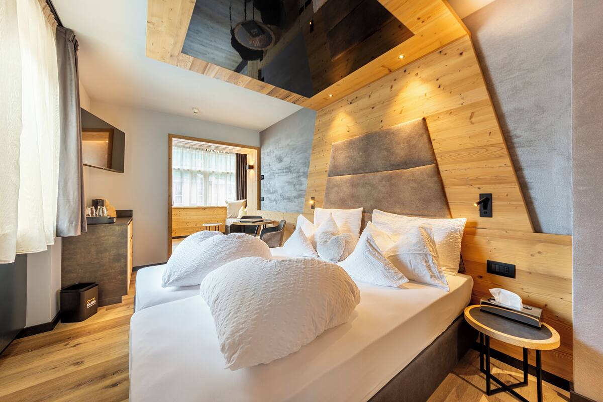A modern hotel room with a large bed, wooden headboard, and a small bedside table.