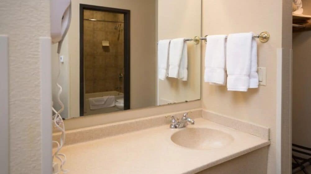A bathroom with a sink, mirror, and towel rack.