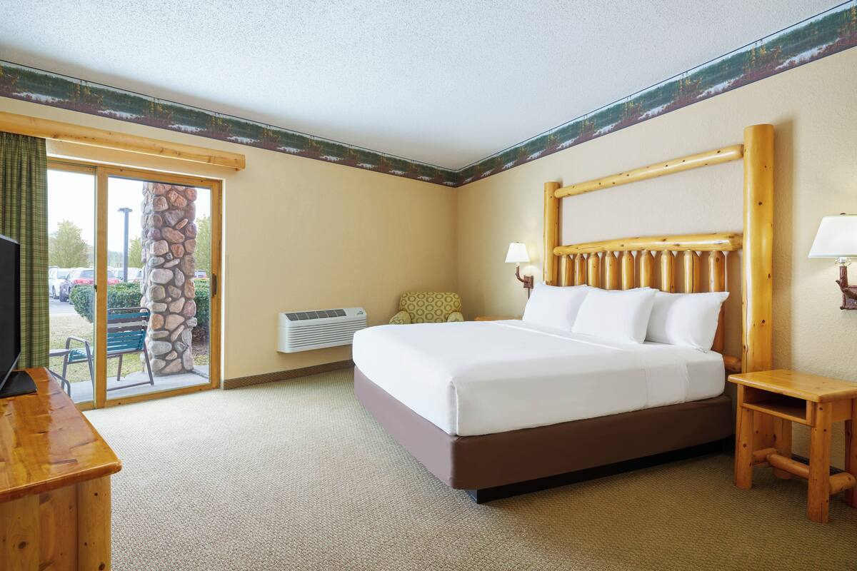 Een hotelkamer met een bed, een bureau, een stoel, een stenen pilaar en uitzicht op het omliggende landschap.