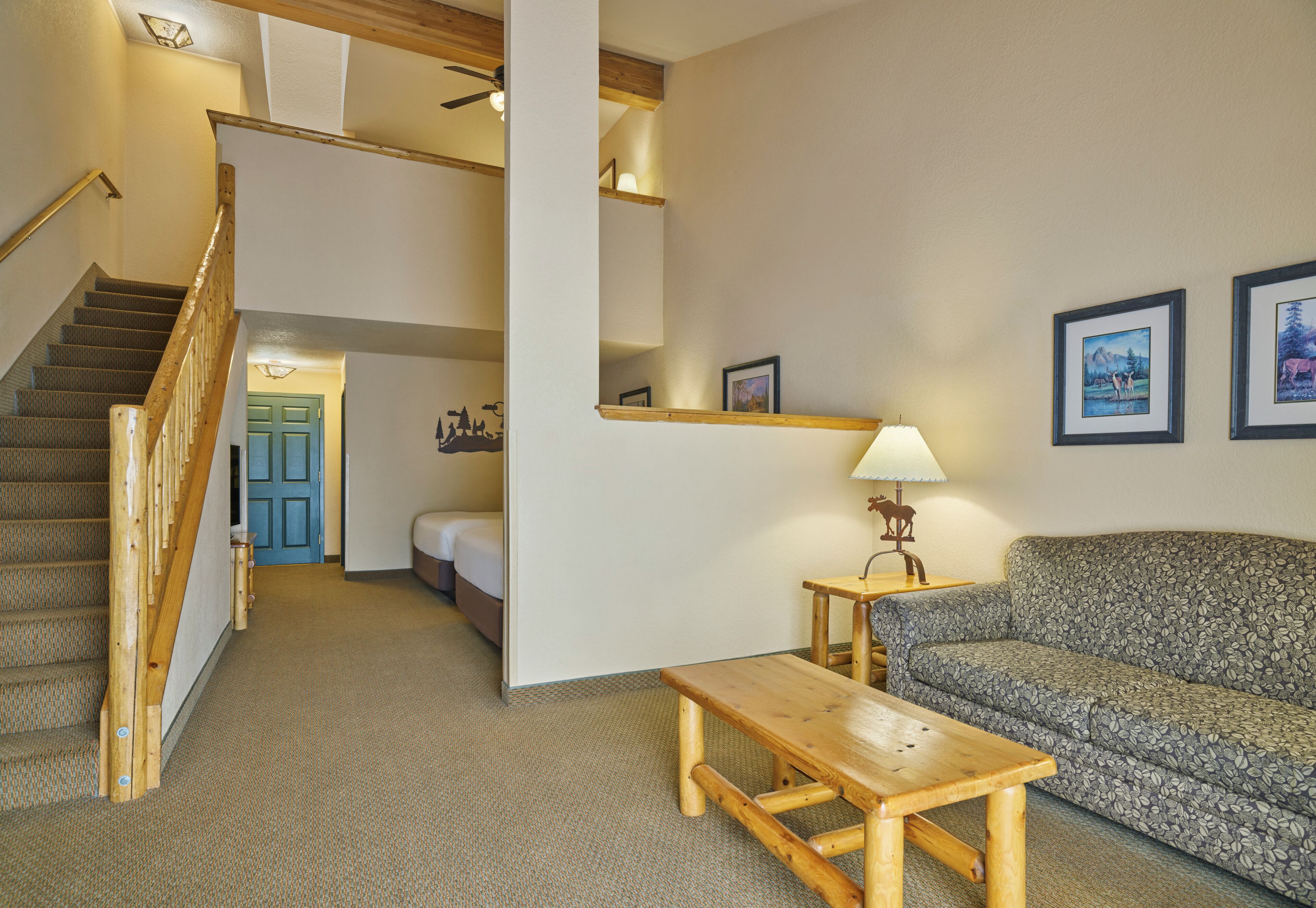 A hotel room with a wooden staircase, a sofa, a small table, and a lamp.