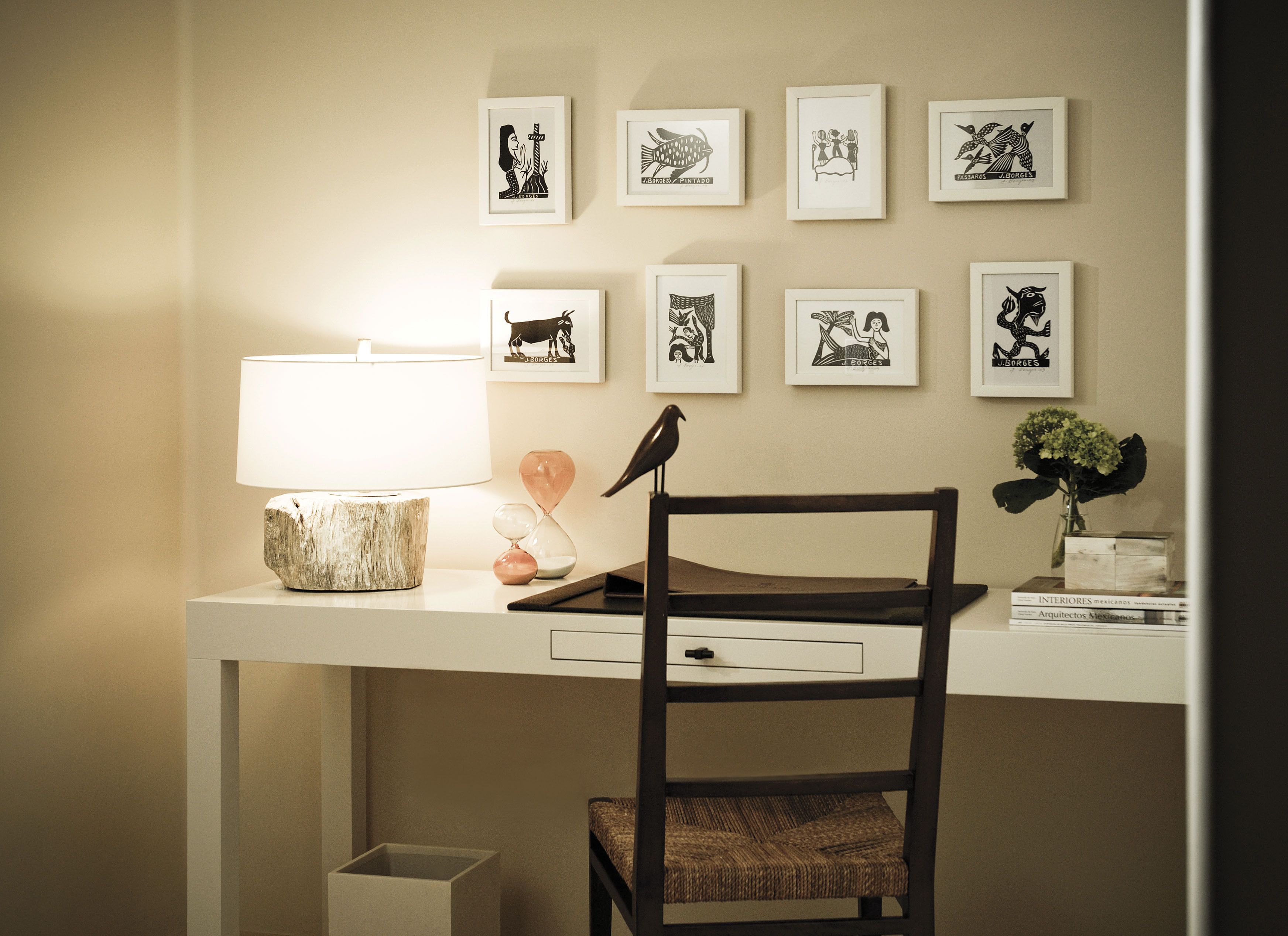 A desk with a lamp, framed artwork, a chair, and a small plant.