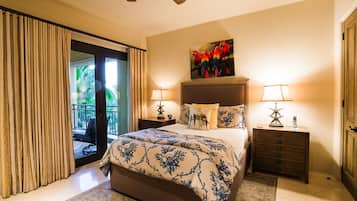 Quarto com uma cama grande, duas mesas de cabeceira com luminárias, um quadro de araras e vista para uma varanda com cortinas.