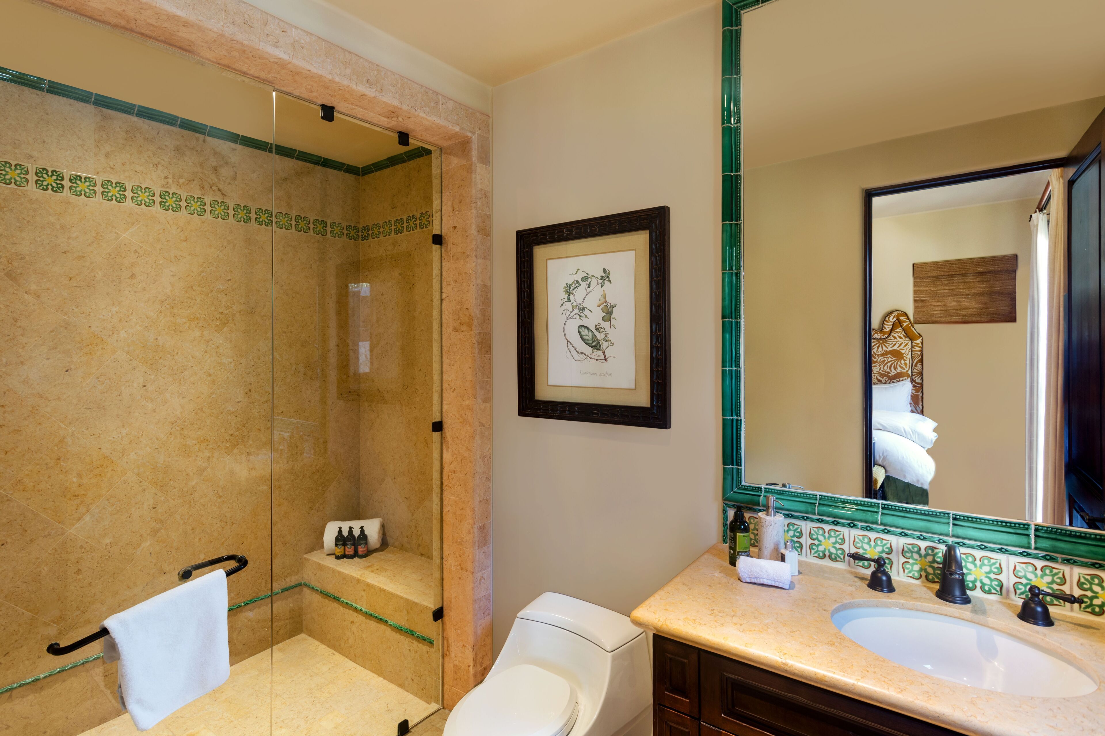 Un baño con ducha de vidrio, inodoro blanco y lavamanos doble con espejo superior.