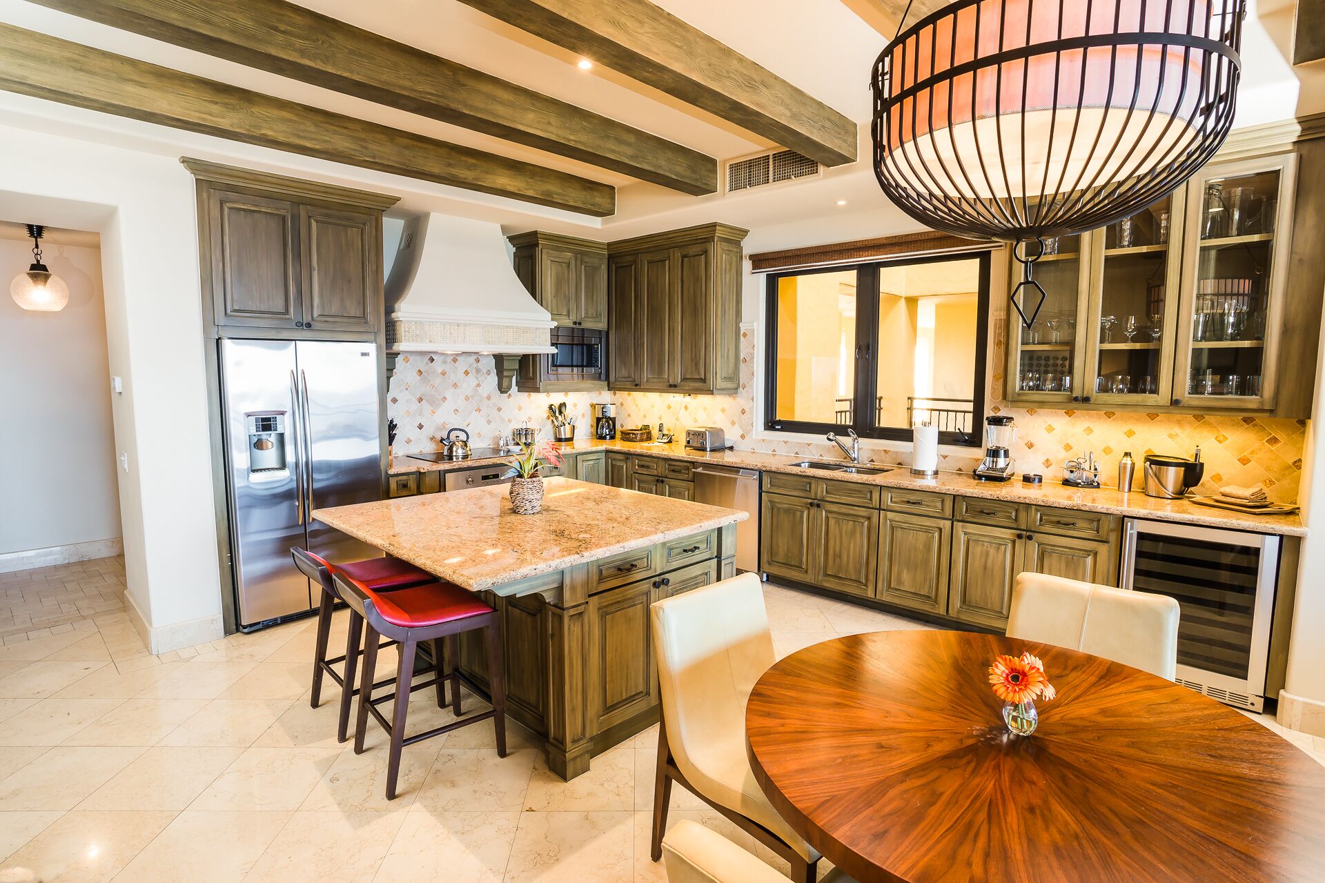A spacious kitchen with a large island, wooden cabinets, and a dining area with a round table.