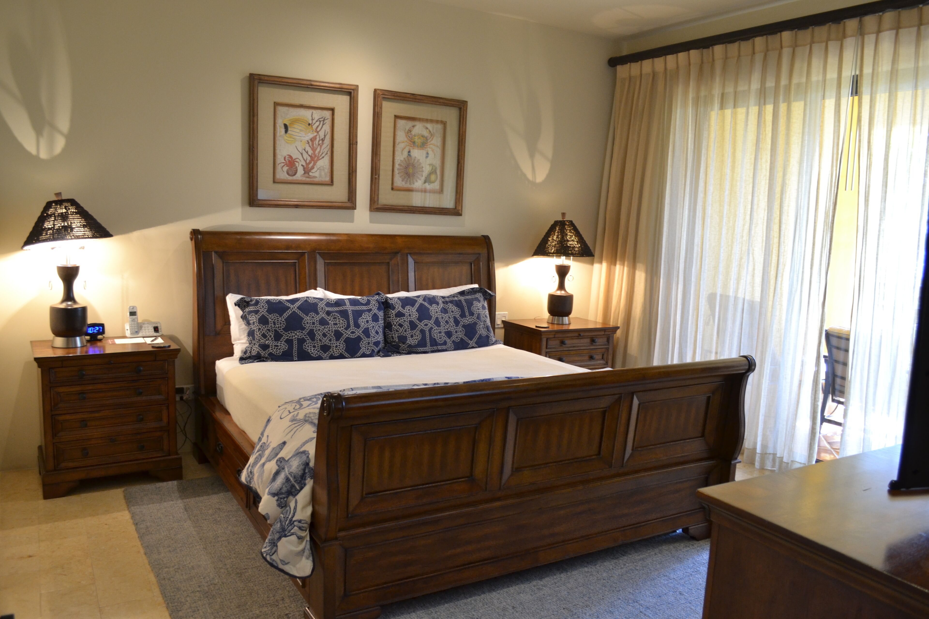A bedroom with a wooden bed, two bedside tables with lamps, a nightstand, and a dresser.