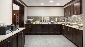 A modern kitchen with dark wood cabinets, a tiled backsplash, and various appliances like a coffee maker and a microwave.