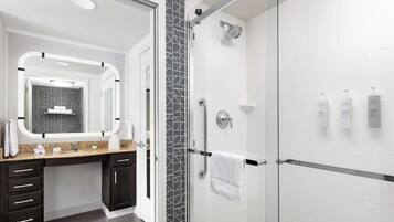A modern bathroom with a glass shower enclosure, a vanity with dark cabinets, and a tiled backsplash.