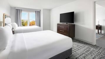 Habitación de hotel con una cama grande, un televisor en una cómoda y vistas a árboles por la ventana.