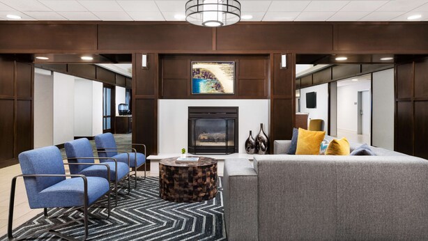 A modern lobby with a fireplace, seating area, and a large artwork above the fireplace.