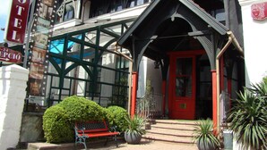 A hotel entrance with a red door, a bench, and potted plants. - Janus Boutique Hotel & Spa (Siófok)