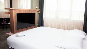 Une chambre d’hôtel avec un grand lit, un meuble en bois pour la télévision, un bureau et une chaise.