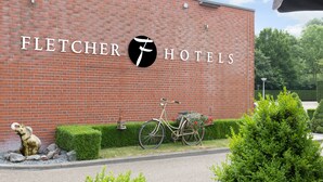 A brick building with the Fletcher Hotels logo, a bicycle with a basket of flowers, and a small elephant statue.