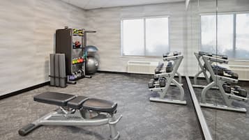 Un gimnasio con una banca, mancuernas y un soporte para pesas.