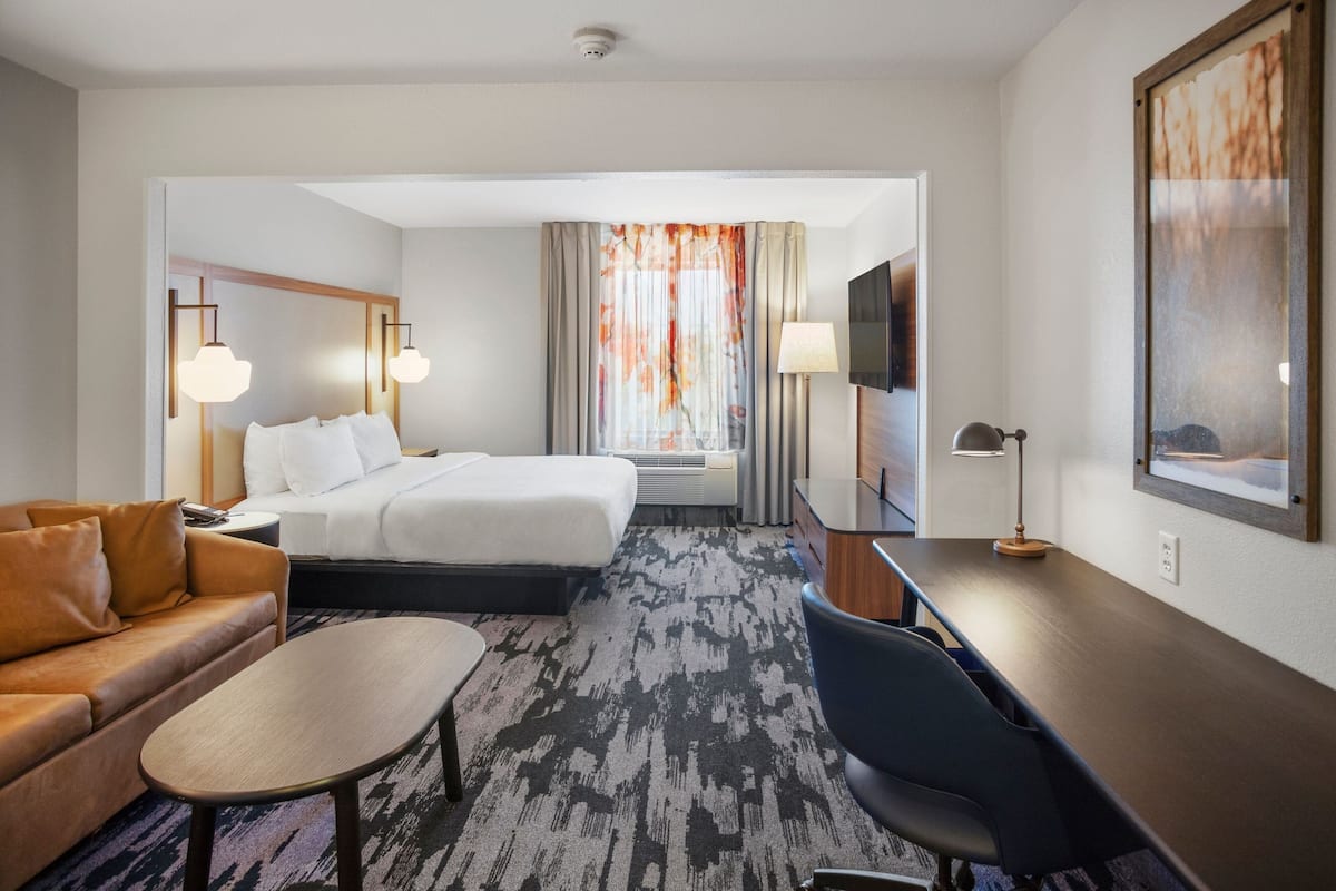 Une chambre d’hôtel avec un lit, un canapé, un bureau et une télévision.