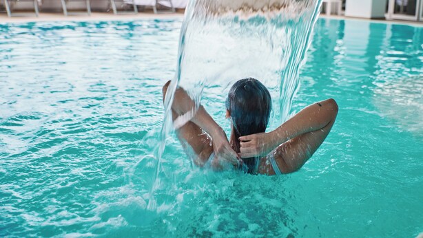 Una persona en una piscina con agua salpicando a su alrededor.