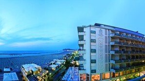 Un hotel con varios balcones, vista al mar y un bar en la azotea.