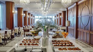 Un comedor formal con varias mesas, elegantes candelabros y un arreglo floral central.