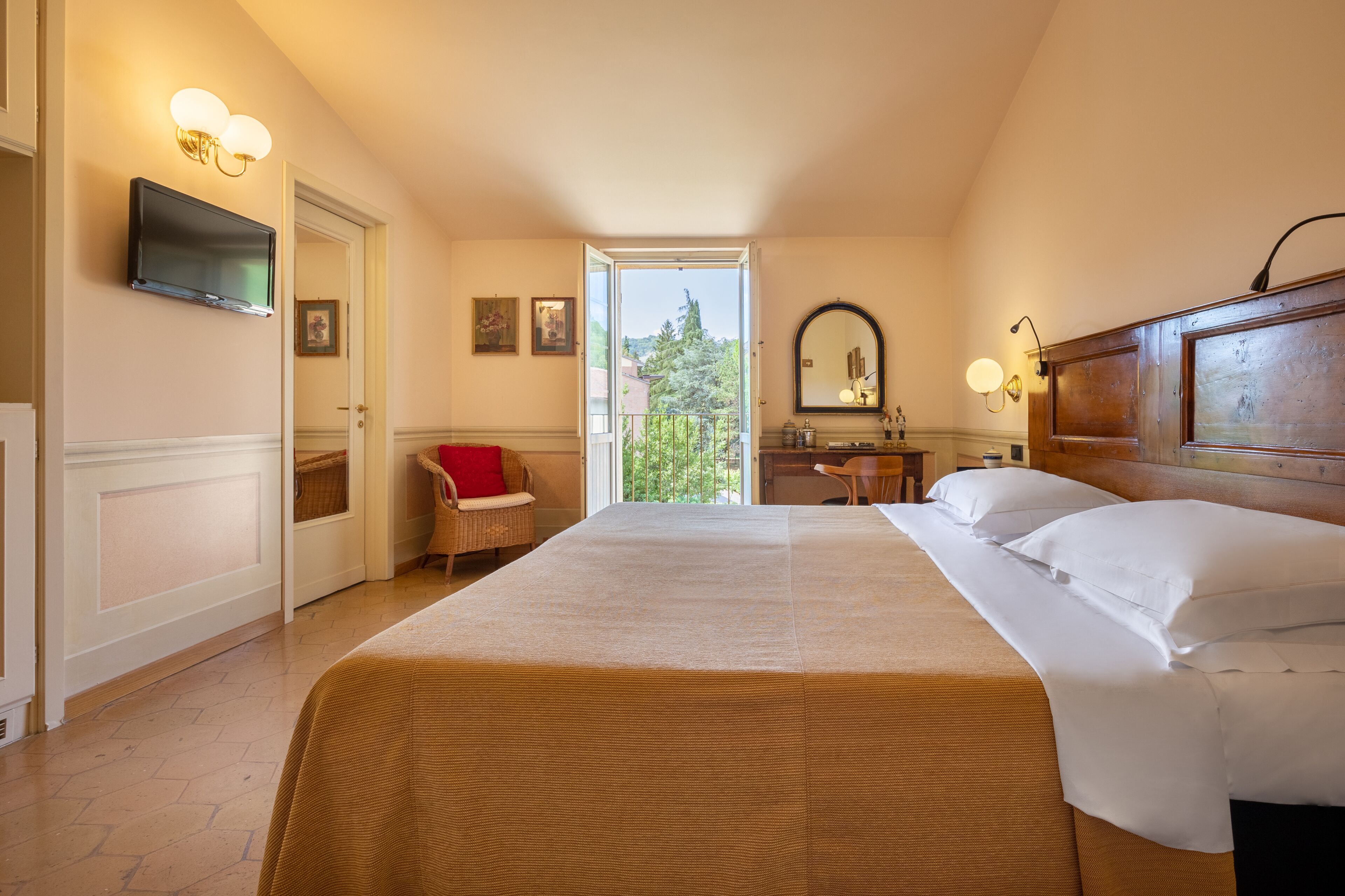 Habitación de hotel con una cama grande, un televisor montado en la pared, una zona de comedor y vistas al exterior.