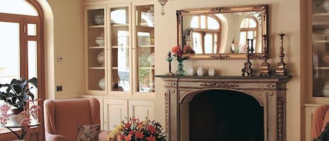 A living room with a fireplace, a chandelier, and a large mirror above it.