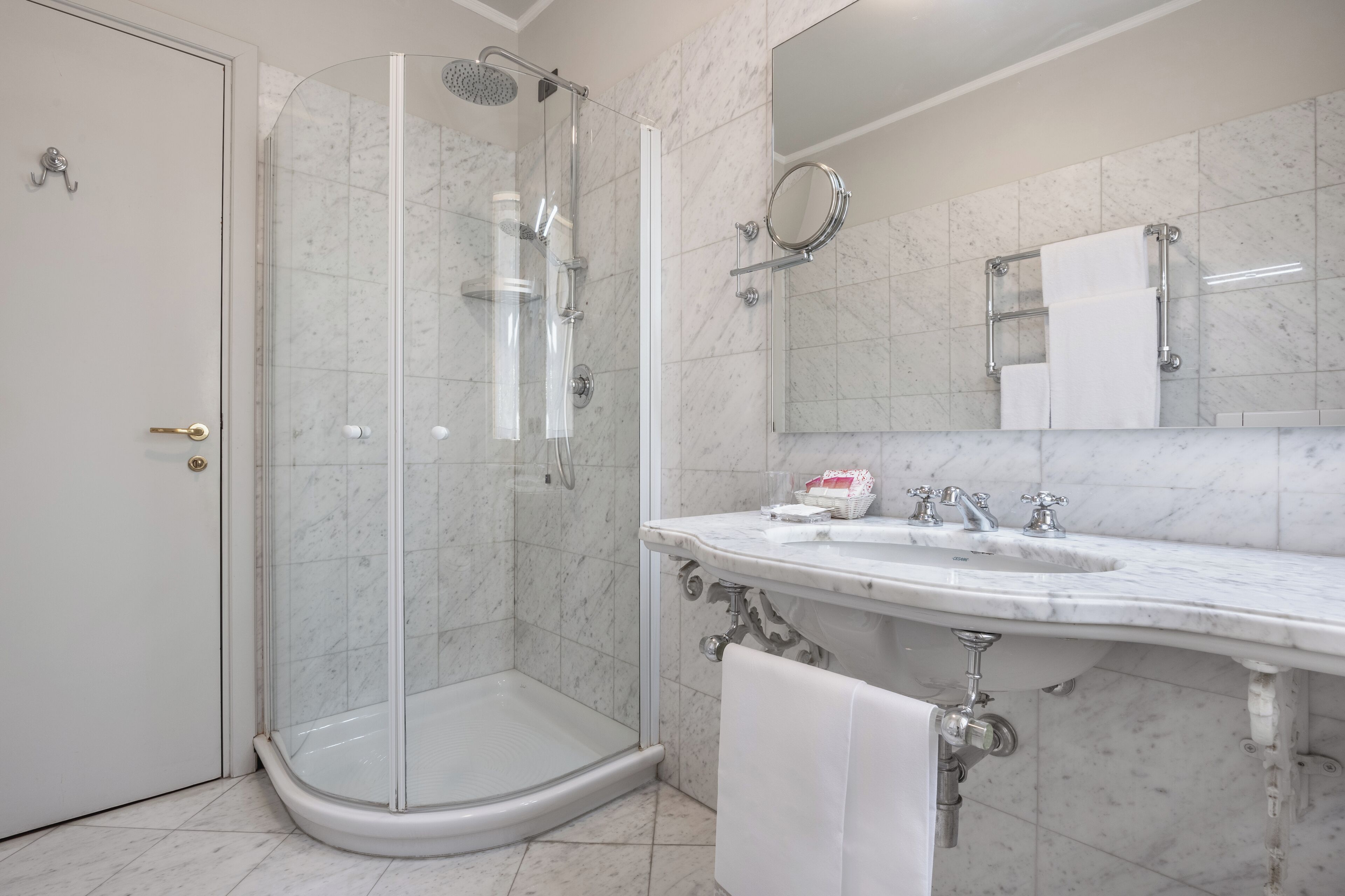 Un baño moderno con ducha de vidrio, lavamanos de mármol y un espejo grande.