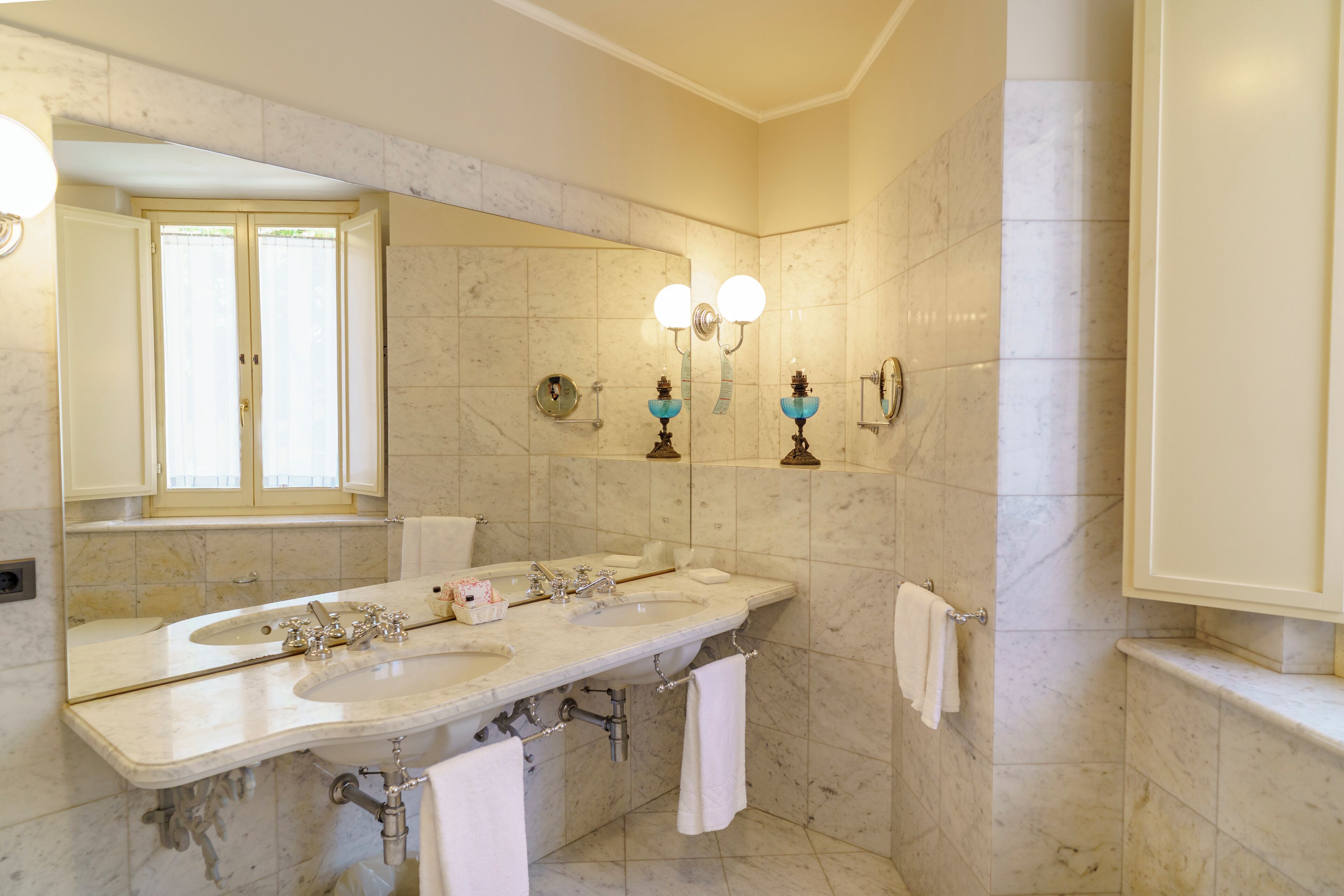 A bathroom with two sinks, a large mirror, and wall-mounted lighting.