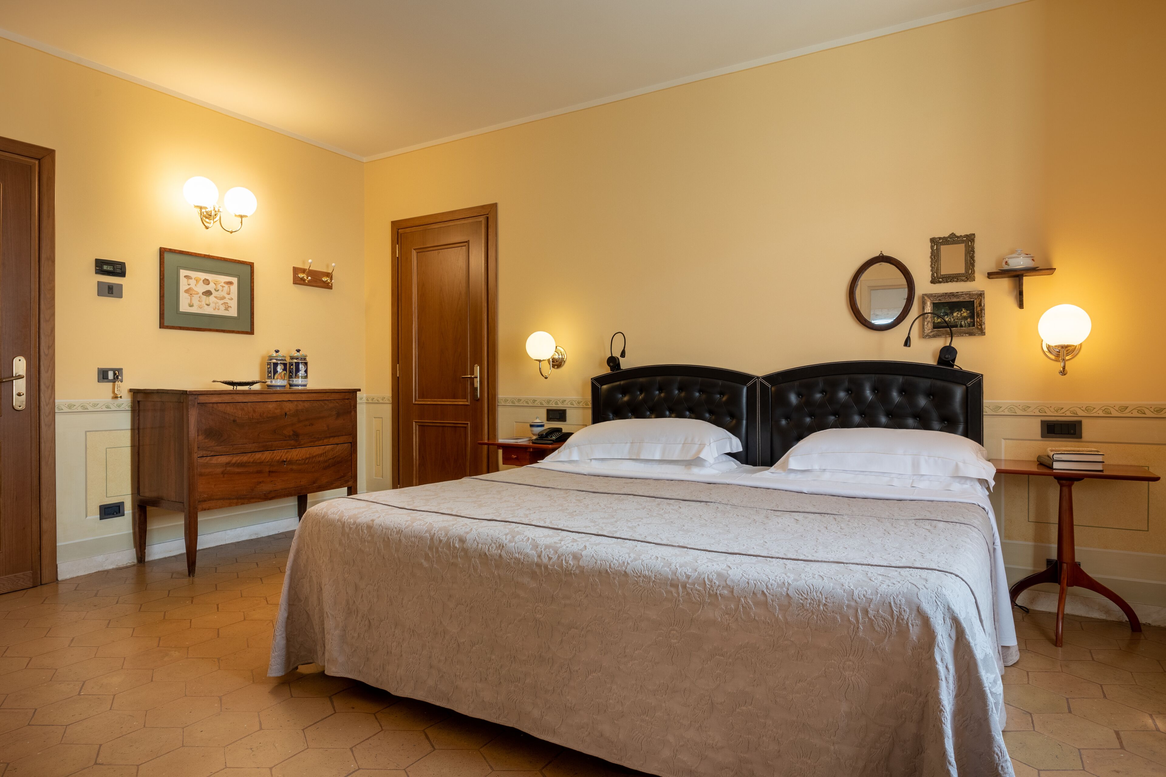 Un dormitorio ordenado con una cama grande, un aparador de madera y una mesita de noche con una lámpara.