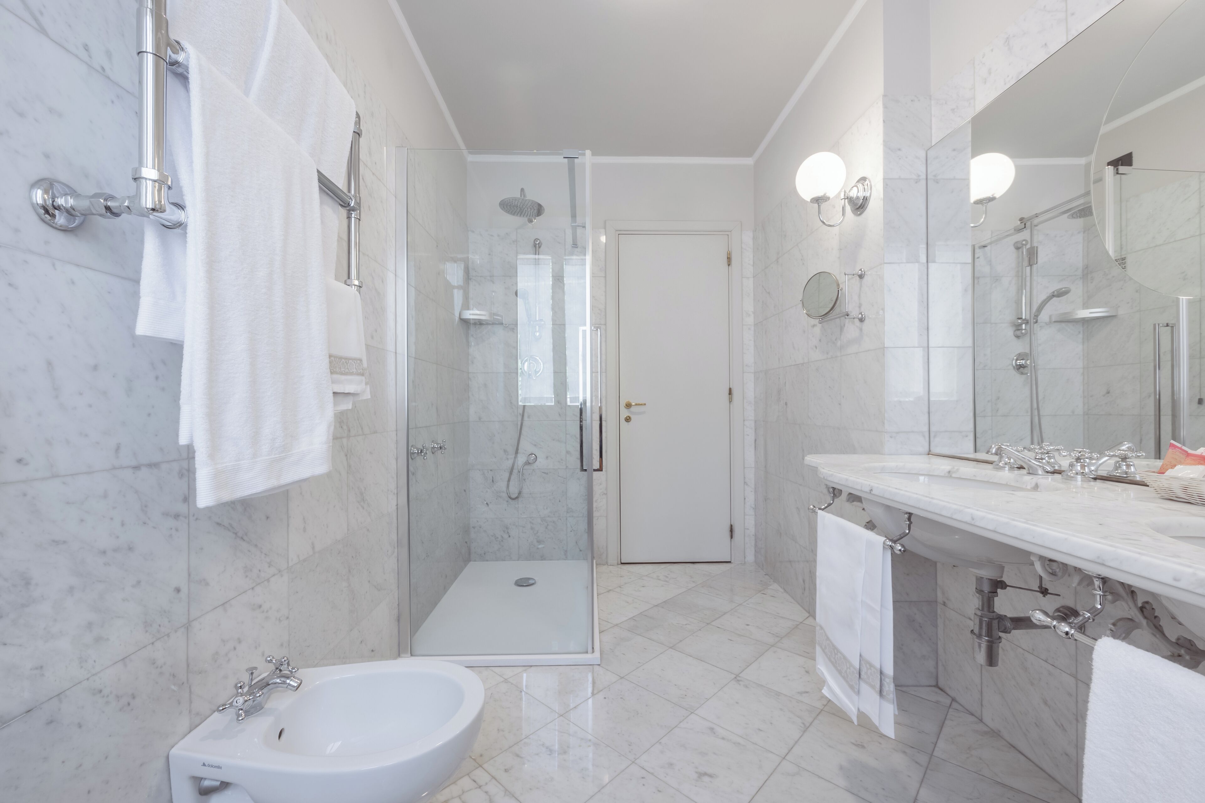 Une salle de bain moderne avec une douche à parois de verre, un meuble-lavabo double et un lavabo sur colonne.