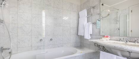 Un baño moderno con una bañera grande, zona de ducha separada y tocador con espejo.