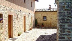 A narrow cobblestone alley between stone buildings with wooden doors and windows. - Hotel Borgo Casato (Castelnuovo Berardenga)