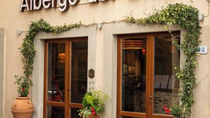 The exterior of Albergo del Chianti with large windows, a sign above the entrance, and two large terracotta pots with plants. - Albergo Del Chianti (Greve in Chianti)