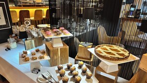 A buffet table with various pastries and desserts, including a large pie and several trays of muffins and croissants. - Albergo Del Chianti (Greve in Chianti)