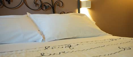 Una cama impecablemente hecha con sábanas blancas y un cabecero decorativo de metal.