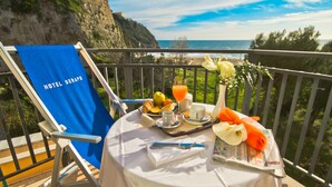 A balcony with a table set for breakfast, overlooking a cliff and the sea. - Hotel Serapo (Gaeta)