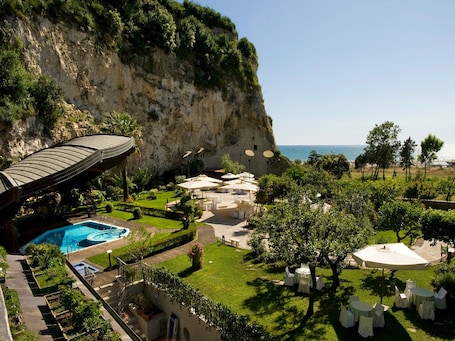 A resort with a pool, outdoor seating, and a view of the sea.