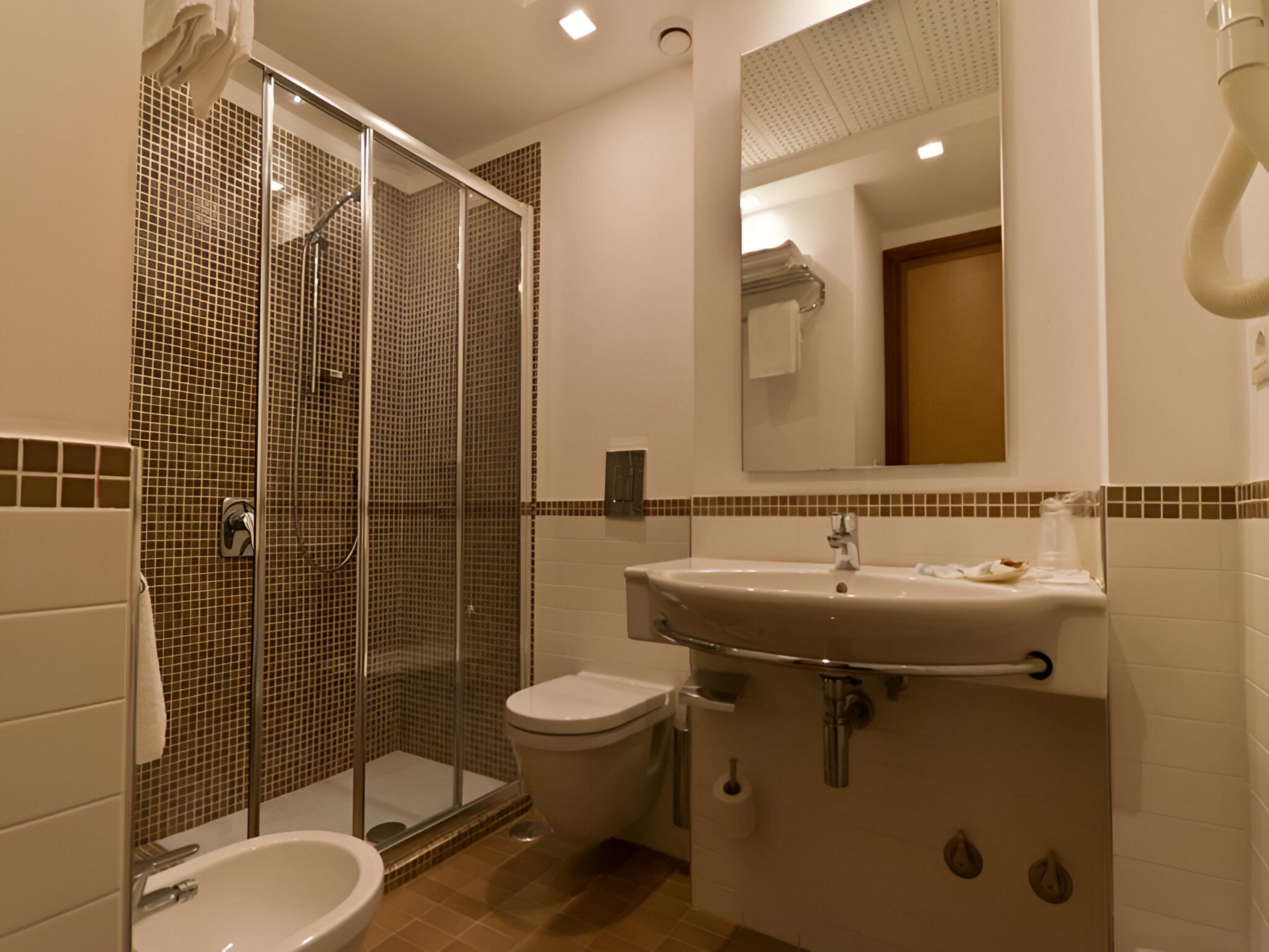 A bathroom with a glass-enclosed shower, a sink, and a toilet.