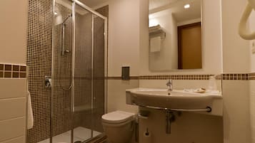 A bathroom with a glass-enclosed shower, a sink, and a toilet.