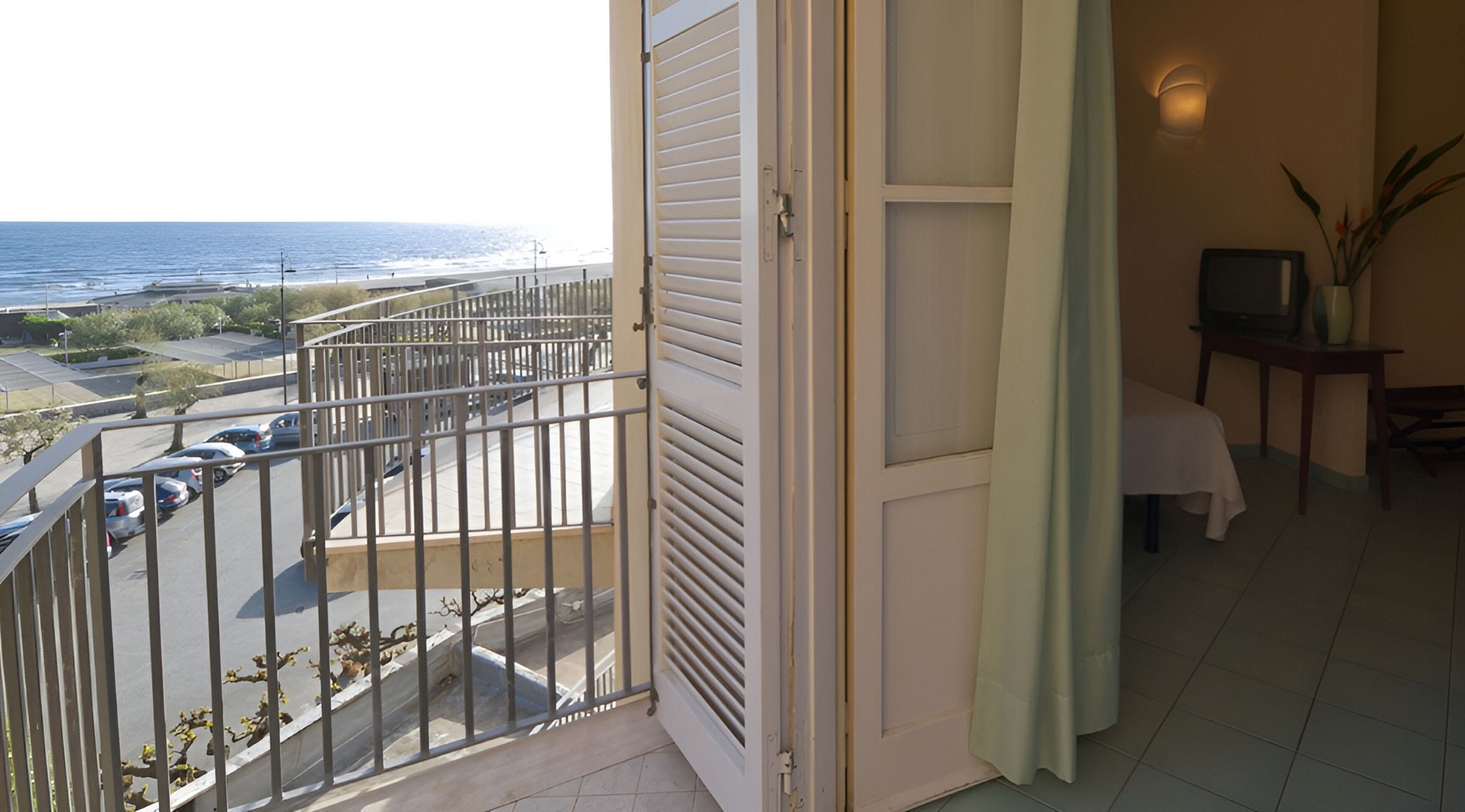 Uma varanda com vista para o mar, uma mesa com uma televisão e uma cadeira.