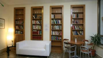A library with bookshelves, a white sofa, and a table with chairs.