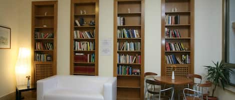 A library with bookshelves, a white sofa, and a table with chairs.