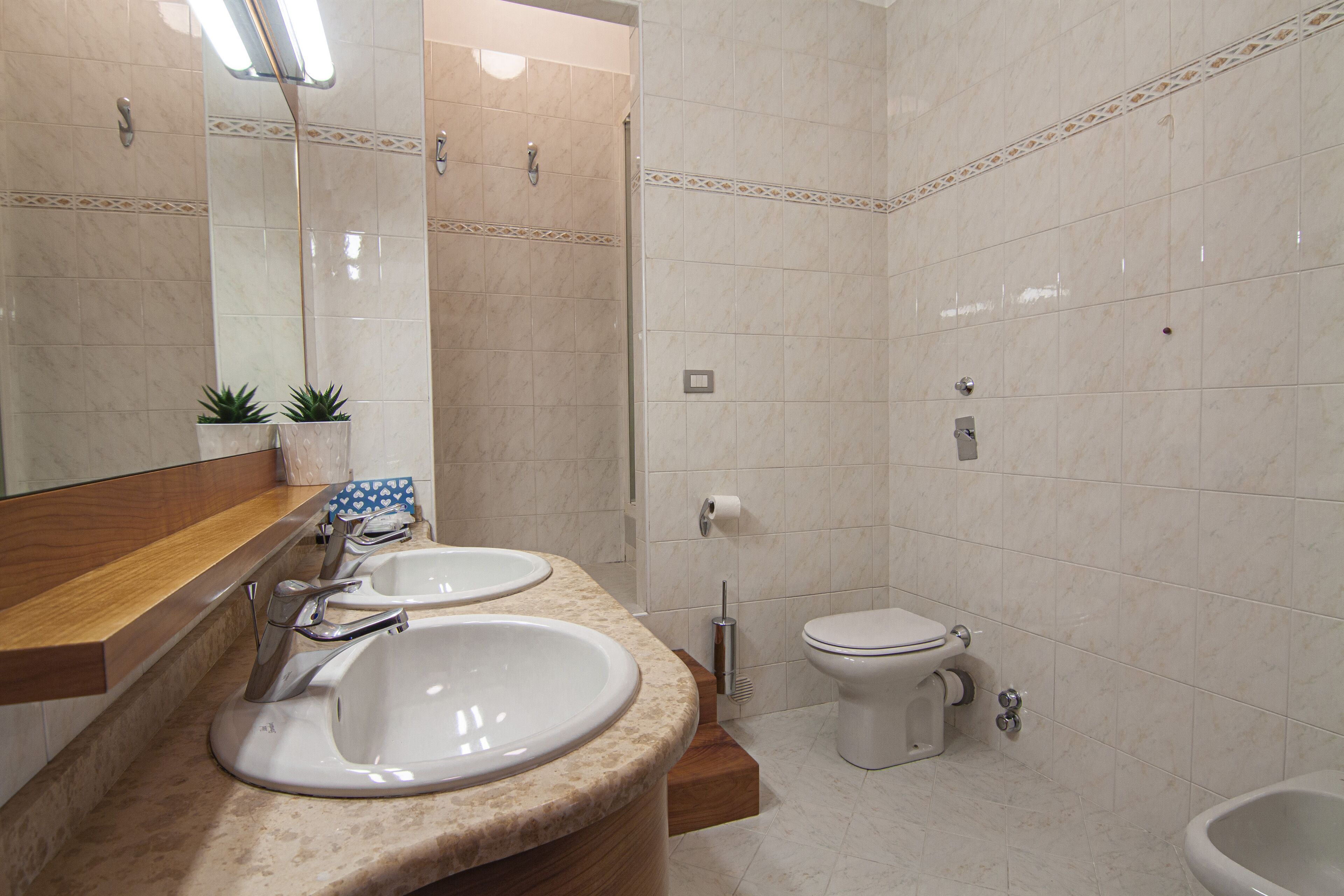 A bathroom with two sinks, a toilet, and a bidet.