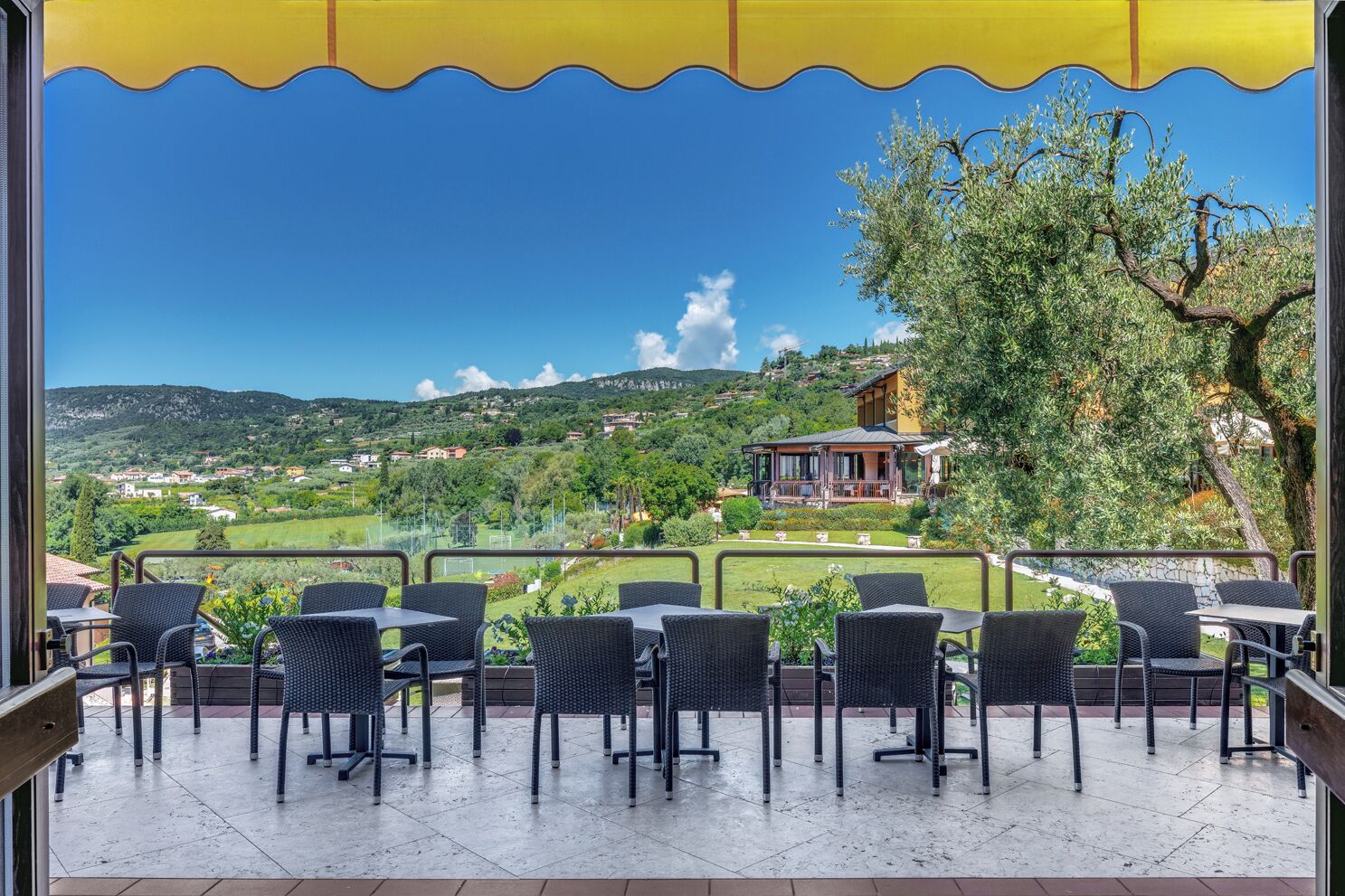 Une terrasse extérieure aménagée avec des meubles en osier, offrant une vue sur un village perché sur une colline.