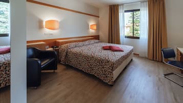 Une chambre d’hôtel avec un lit, un bureau, une chaise et une fenêtre avec des rideaux.