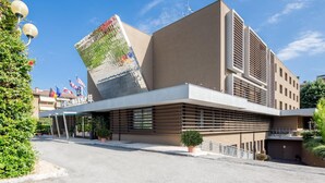 A modern building with a sloped roof, large windows, and a prominent vertical structure.